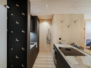 A modern kitchen with a wooden interior, a marble countertop, and a view of a snowy landscape.