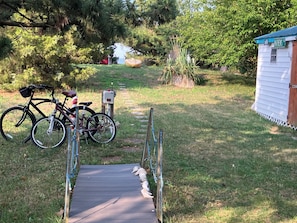 A wooden bridge, a bicycle, and a small shed in a grassy area.