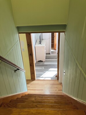 A wooden staircase leading to a room with a white cabinet and a desk.