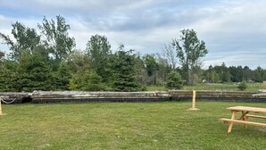 A grassy outdoor area with a picnic table and a stone wall in the background. - Fantastic campground retreat #35 (Lion's Head)