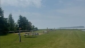 A grassy area with picnic tables and a signpost. - Fantastic campground retreat #35 (Lion's Head)