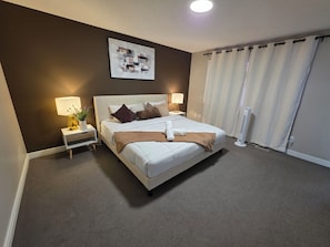 A neatly arranged hotel room with a large bed, bedside lamps, a wall-mounted artwork, and a window with curtains. - Large, cozy, and family-ready. This spacious 4-bedroom 5 bed, 2.5-bath house (Edmonton)