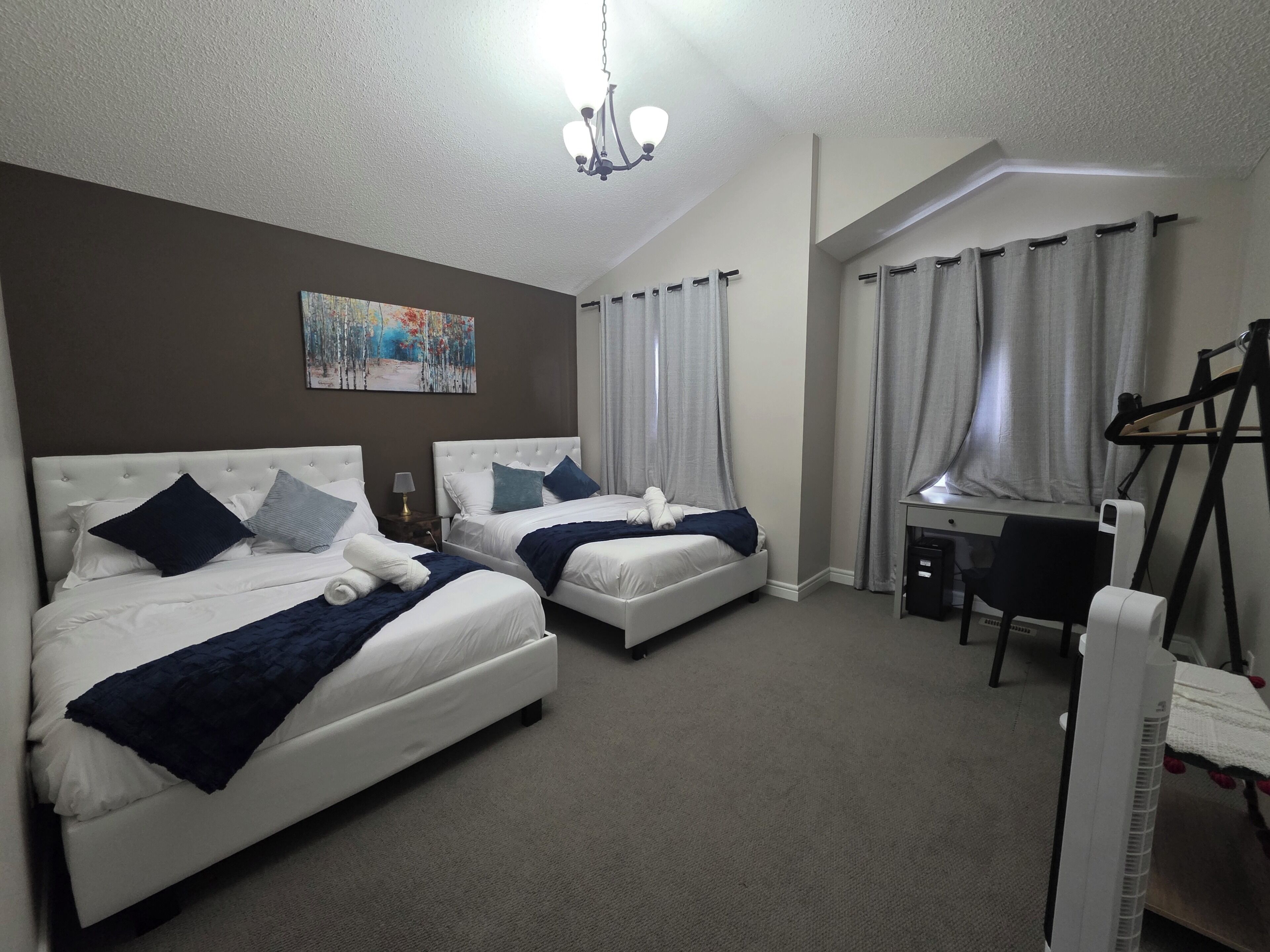 Ein Hotelzimmer mit zwei Betten, einem Schreibtisch, einem Sessel, einem Heizkörper und einem Bild an der Wand.