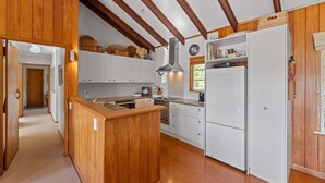 Eine Küche mit Holzbalken, weißen Schränken, einer zentralen Kochinsel und einem Kühlschrank.