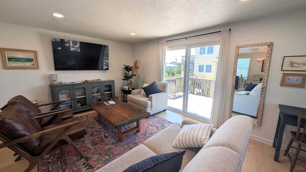 A living room with a sofa, a coffee table, a TV, a cabinet, and a balcony with a view. - The Hatch: New to the Program, Close to the Beach, Pet-Friendly (Avon)
