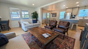 A living room with a sofa, coffee table, and chairs, a dining area with a table and chairs, and a kitchen with cabinets and appliances. - The Hatch: New to the Program, Close to the Beach, Pet-Friendly (Avon)