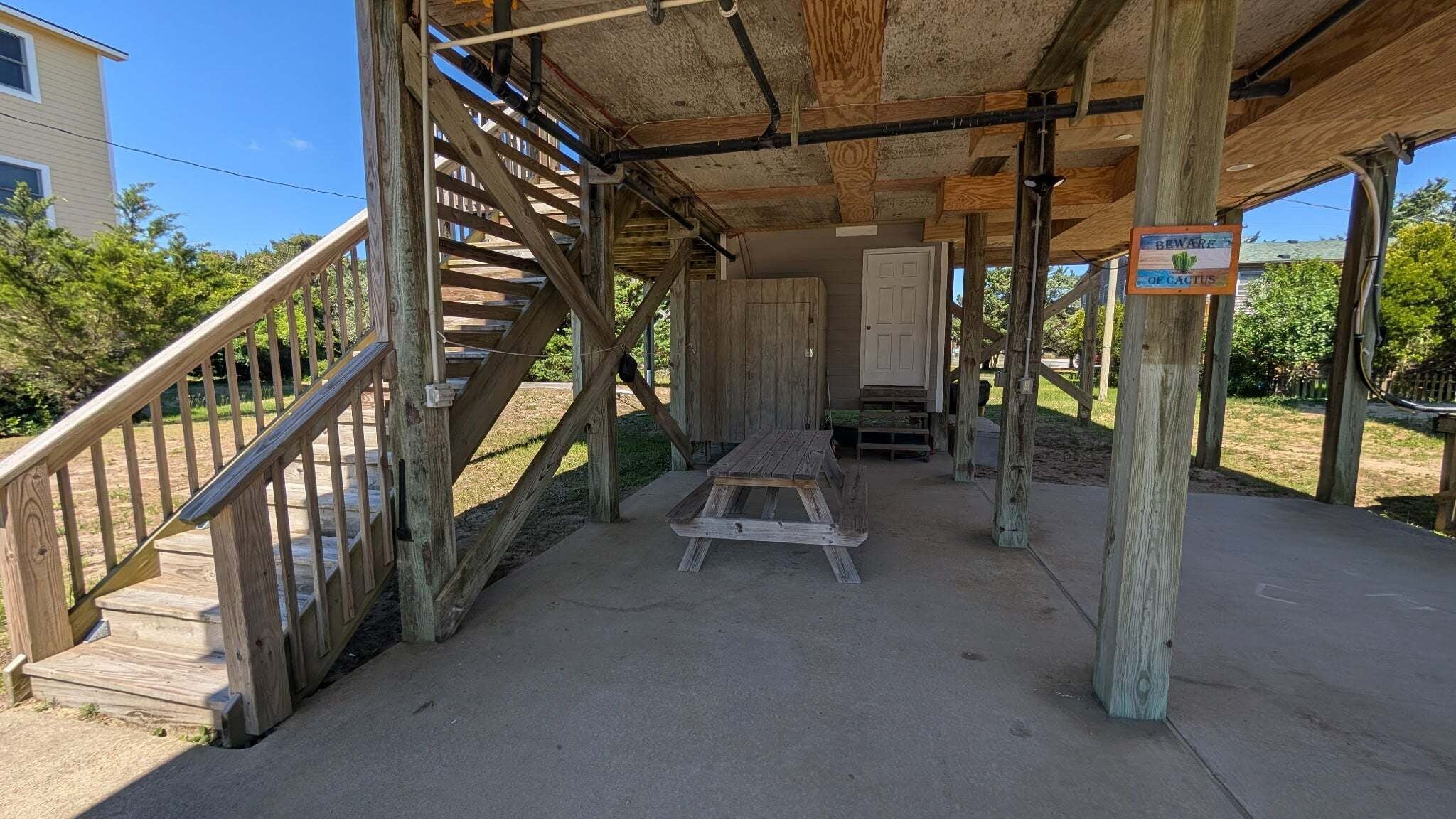 Una escalera de madera que lleva a un espacio cubierto con un banco y una puerta.