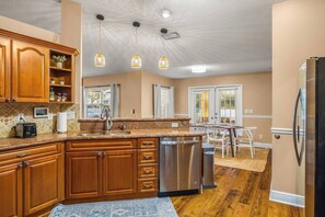 A kitchen with wooden cabinets, a stainless steel dishwasher, and pendant lights. - Walk to Beach · Hot Tub, Fire Pit & Game Room · Sleeps 10, Dogs Welcome (Seminole)