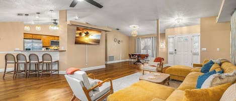 A spacious living area with a kitchen, dining area, and a large sofa.
