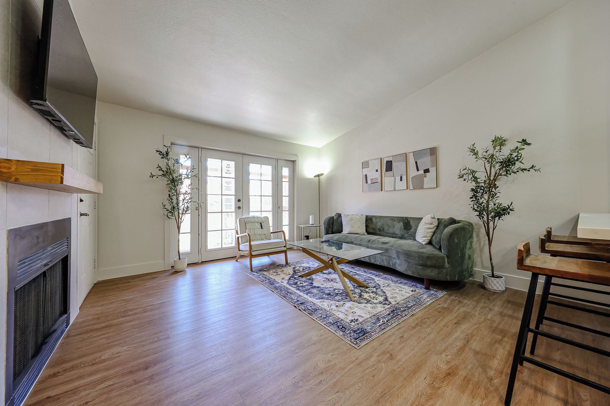 A spacious living room with hardwood flooring, a fireplace, a green sofa, and a coffee table.