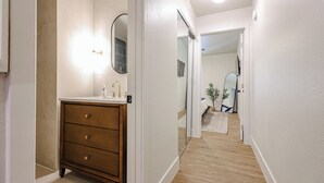A modern bathroom with a wooden vanity, a mirror, and a light fixture. - Olive & Oak Retreat King Bed Pool Fast WiFi (Phoenix)