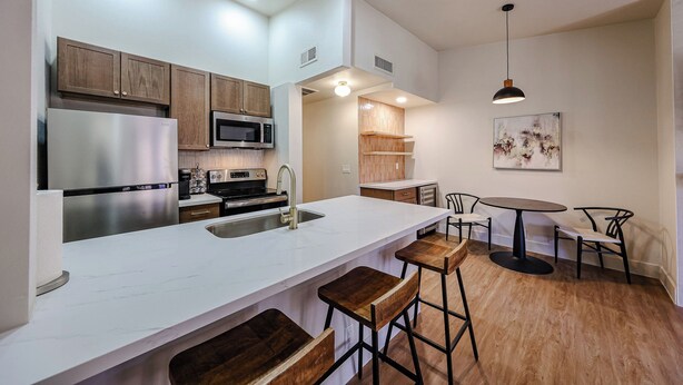 A modern kitchen with a large island, bar stools, a dining table, and a pendant light. - Olive & Oak Retreat King Bed Pool Fast WiFi (Phoenix)