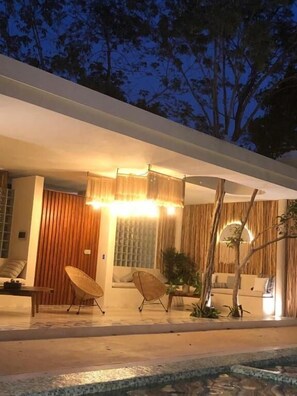 A modern house with a pool, outdoor seating, and a well-lit entrance. - Carmela  (Tulum)