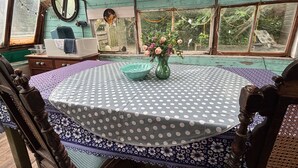 Um quarto aconchegante com uma mesa redonda, uma cadeira, cômoda, espelho e janela com vista para o verde.