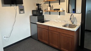 A compact kitchen with a built-in microwave, a coffee maker, a sink, and a small refrigerator. -  Room 24. Angry Salmon Inn, Micro Efficiency. (Anchor Point)