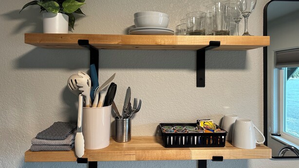A kitchen shelf with utensils, a plant, and kitchenware. -  Room 24. Angry Salmon Inn, Micro Efficiency. (Anchor Point)
