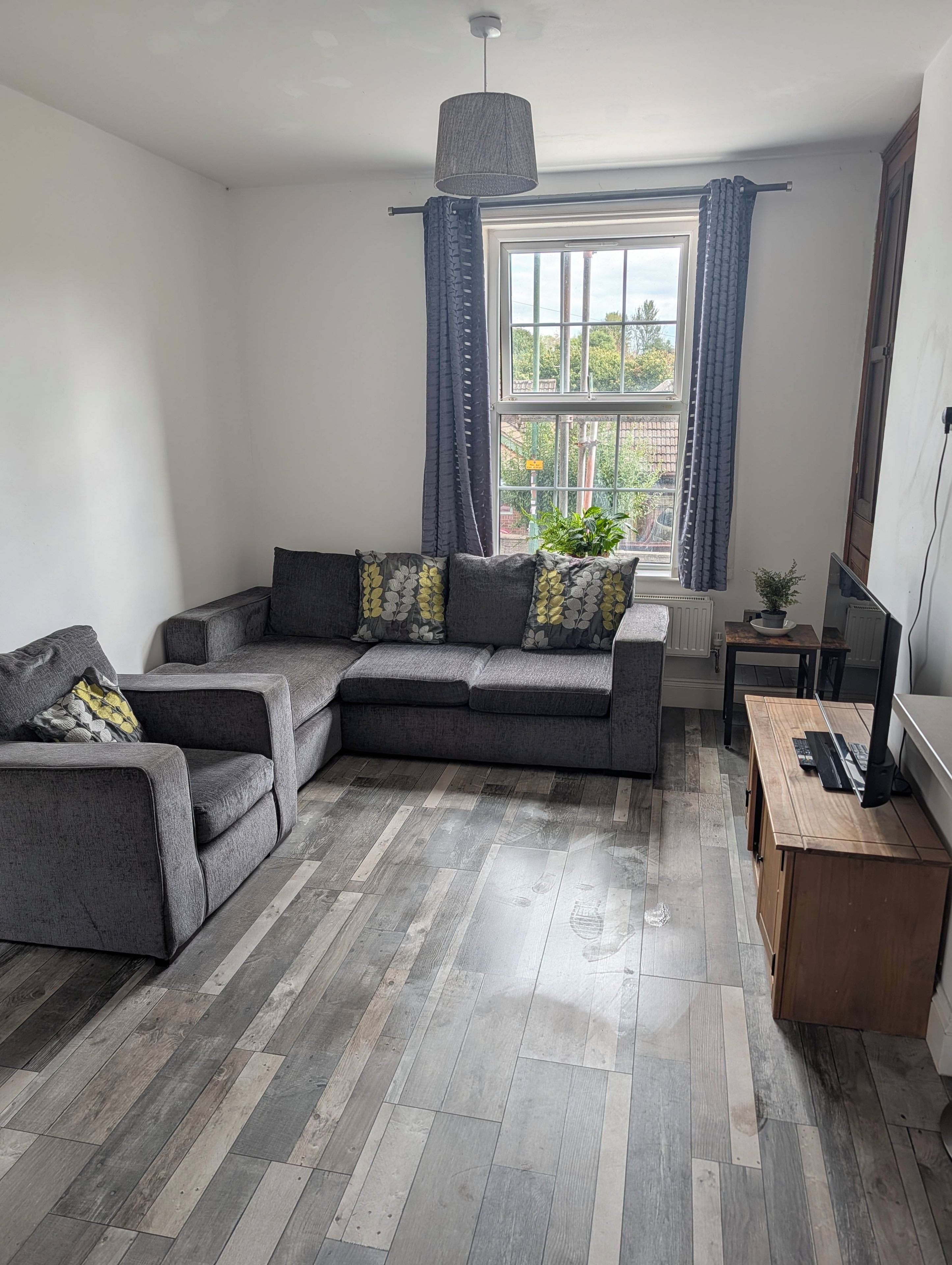 Una sala moderna con un sofá modular, una mesa de centro de madera y un televisor sobre un mueble.