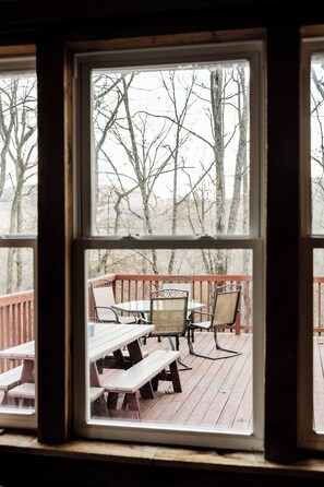 A deck with wooden benches and chairs, overlooking a forested area.