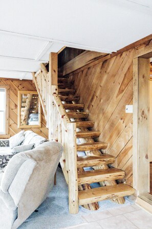 Eine Holztreppe in einem Zimmer mit einem Bett und einem Fenster.