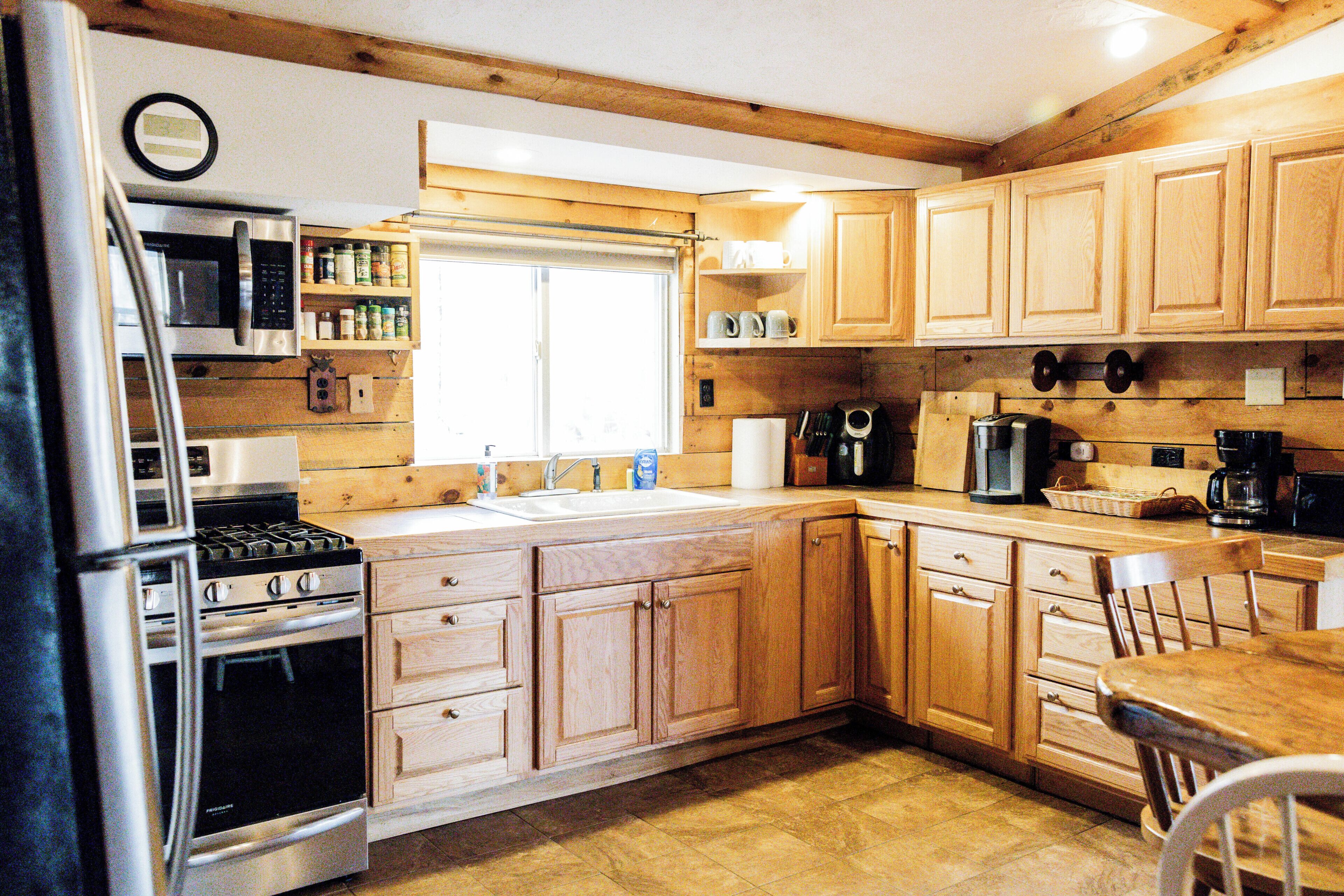 A kitchen with wooden cabinets, stainless steel appliances, and a window.