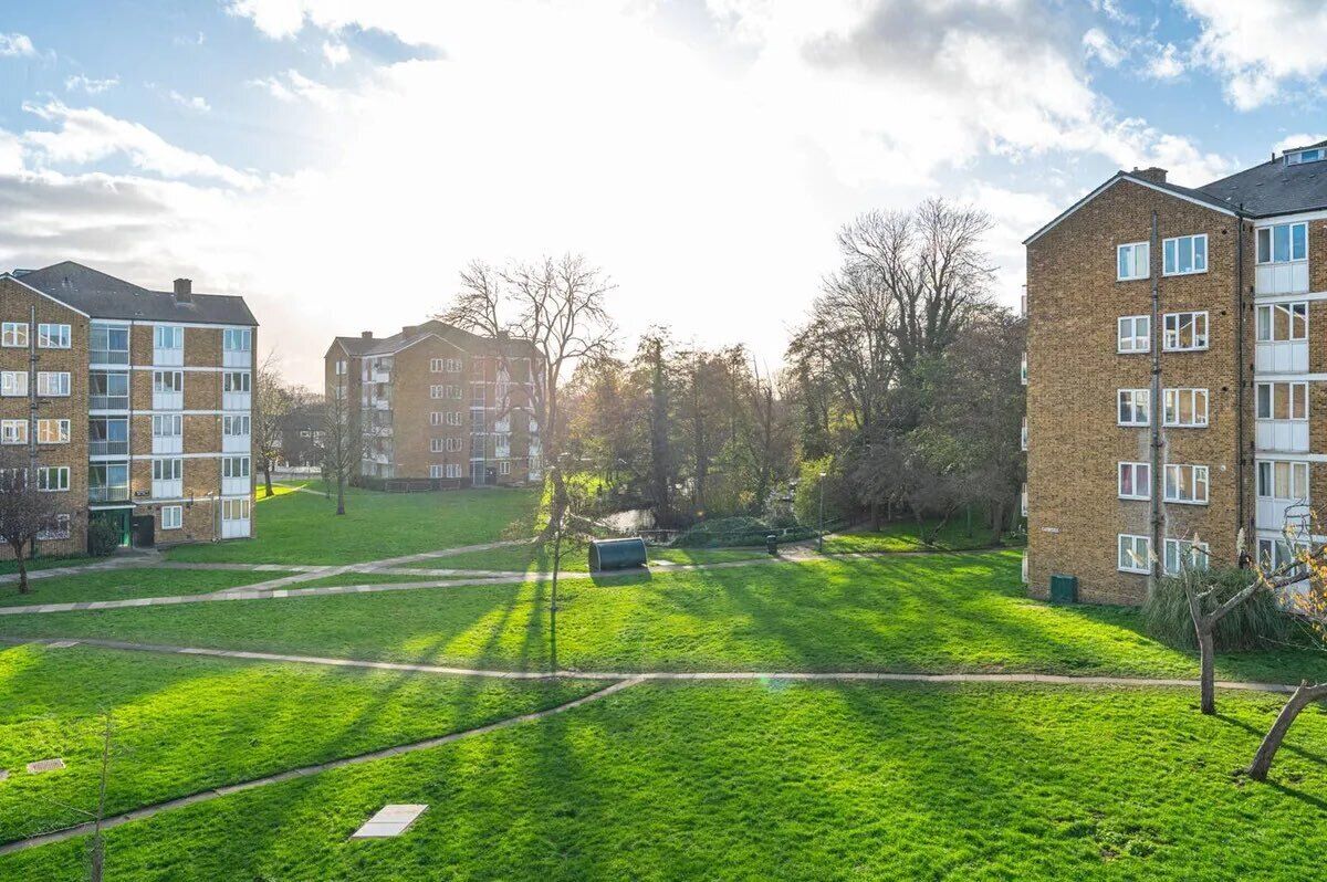 A residential area with multi-story buildings, a grassy field, and a pathway.
