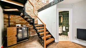 Een modern interieur met een houten trap, een bakstenen muur, en een keuken met kasten en een koelkast.