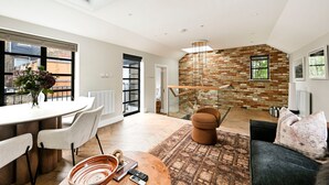 Een modern interieur met een eethoek, een zithoek, een trap en een bakstenen muur.