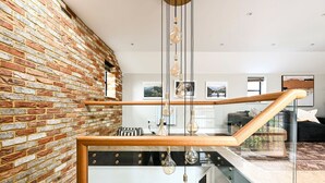 Een modern interieur met blootliggende bakstenen muren, een houten trap en hangende lampen.