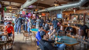A bar with wooden tables and chairs, a counter with a bartender, and a neon sign. - 2BR Garden Pool Home❤️ Walk to Barton Springs, Zilker & Dining (Austin)