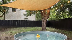 A metal water tank with a rubber duck, surrounded by a tree and a black fence. - 2BR Garden Pool Home❤️ Walk to Barton Springs, Zilker & Dining (Austin)