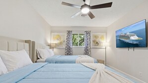 A hotel room with two beds, a ceiling fan, a TV displaying a cruise ship, and a window with curtains. - 2BR Garden Pool Home❤️ Walk to Barton Springs, Zilker & Dining (Austin)