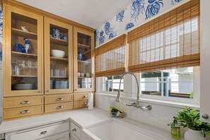 A kitchen with wooden cabinets, a sink, and a window with blinds. - Bella Azul - Charming Home Minutes from Campus (Eugene)