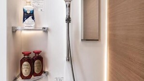 A shower with a handheld showerhead, a wall-mounted mirror, and two shelves with toiletries.