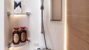 Una ducha con cabezal de ducha de mano, un espejo instalado en la pared y dos estantes con artículos de aseo.