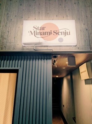 Um corredor com uma placa indicando 'Star Minami Senju' e uma porta que dá para um quarto.