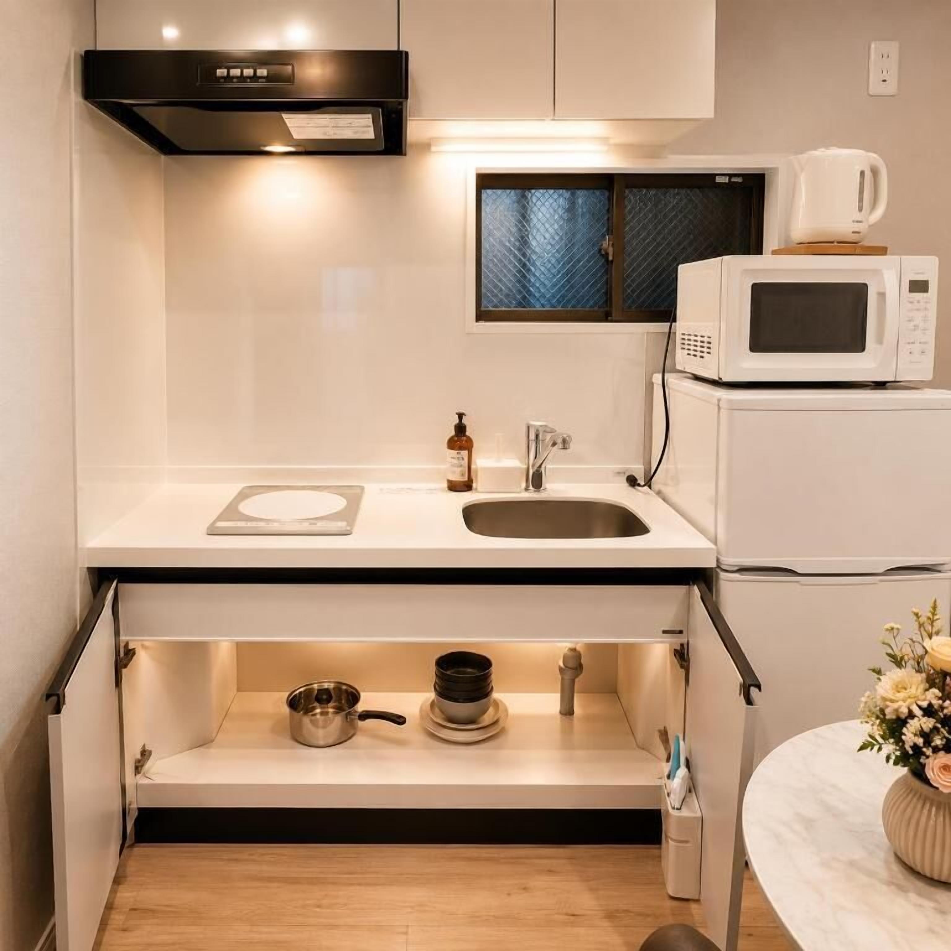 A compact kitchen with a microwave, sink, and a window above the countertop.