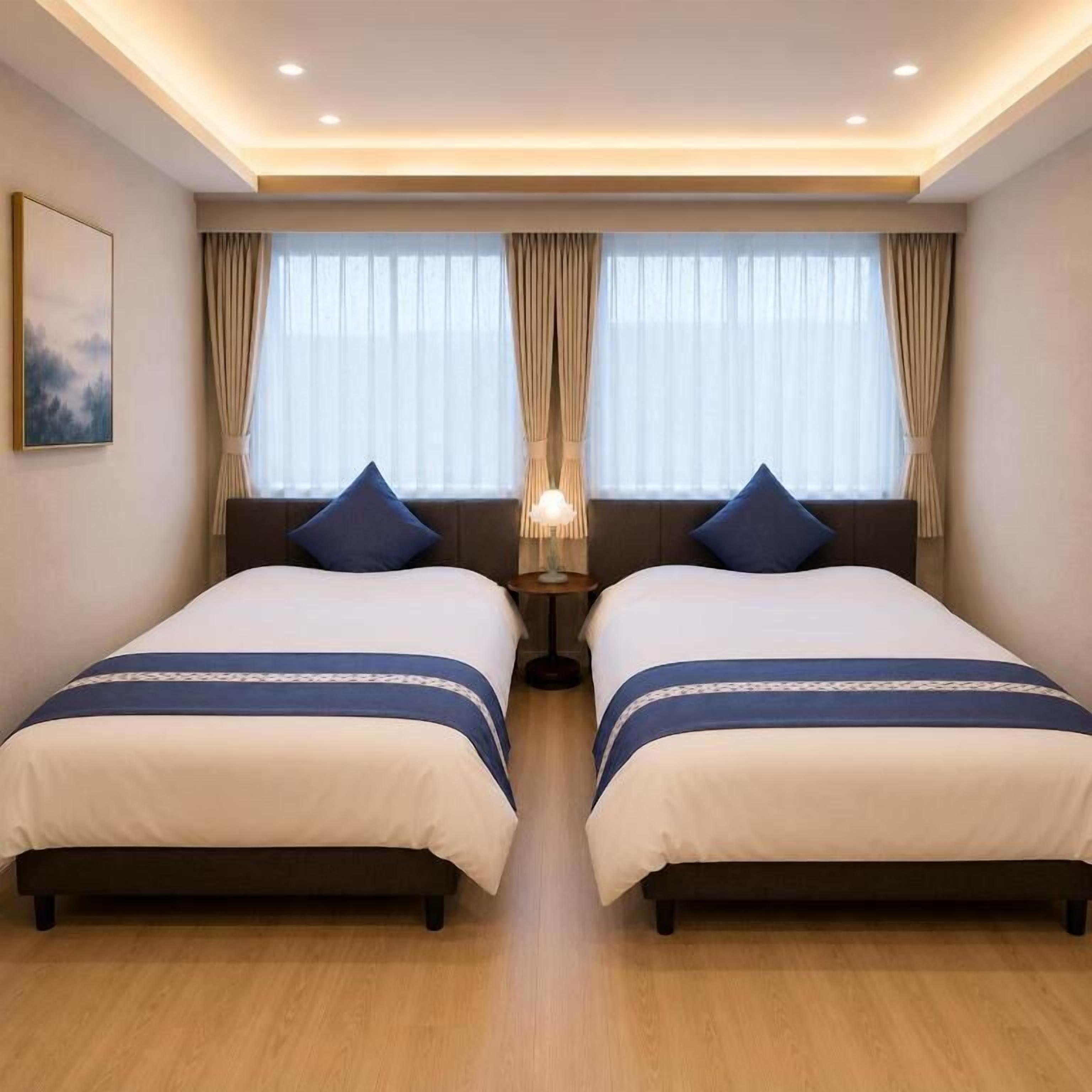 Ein Hotelzimmer mit zwei Betten, einem Nachttisch, einer Lampe und einem Bild an der Wand.