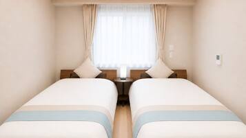 A hotel room with two beds, a small table, a window with curtains, and a ceiling light.