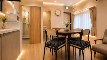 Una habitación de hotel moderna con comedor, una puerta de madera, un reloj y un jarrón con flores.