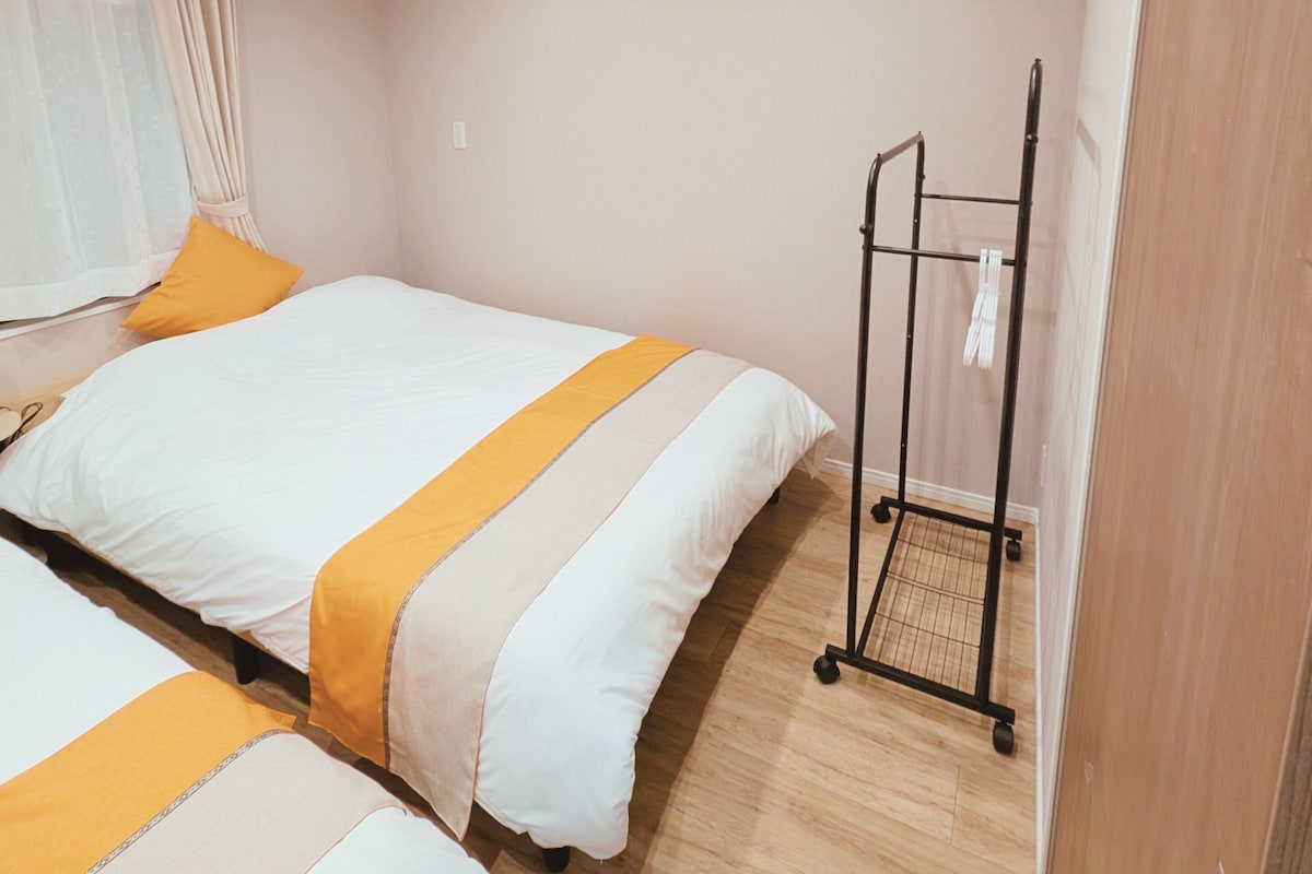 A hotel room with two beds, an air conditioning unit, a wardrobe, and a small trolley.