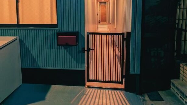 A hotel entrance with a sign reading 'Star Minami Senju,' a metal gate, and a narrow corridor leading inside.