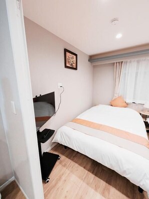 A bedroom with a bed, a bedside table, a wall-mounted TV, and a window with curtains. - Star Minami-Senju (Taito-ku)