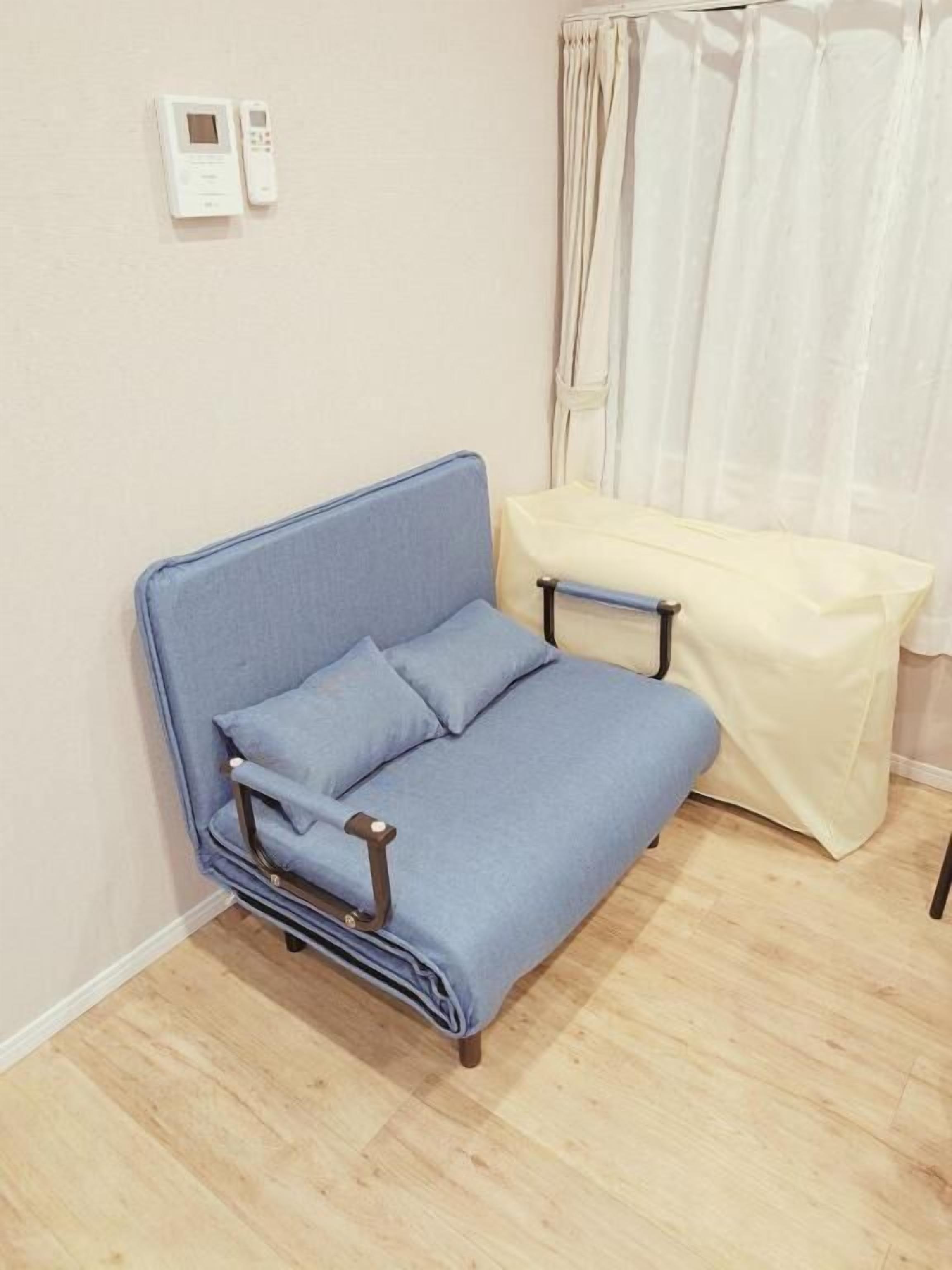 A room with a blue sofa, a small table with a white tablecloth, and a curtain.