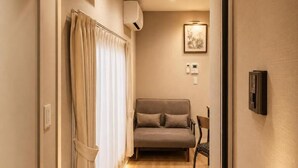 A hallway with a sofa, a pair of slippers, a plant, and a framed picture on the wall.