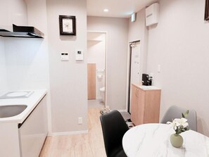 A modern kitchen with a sink, a dining table with chairs, a cabinet, and a framed picture on the wall. - Star Minami-Senju (Taito-ku)