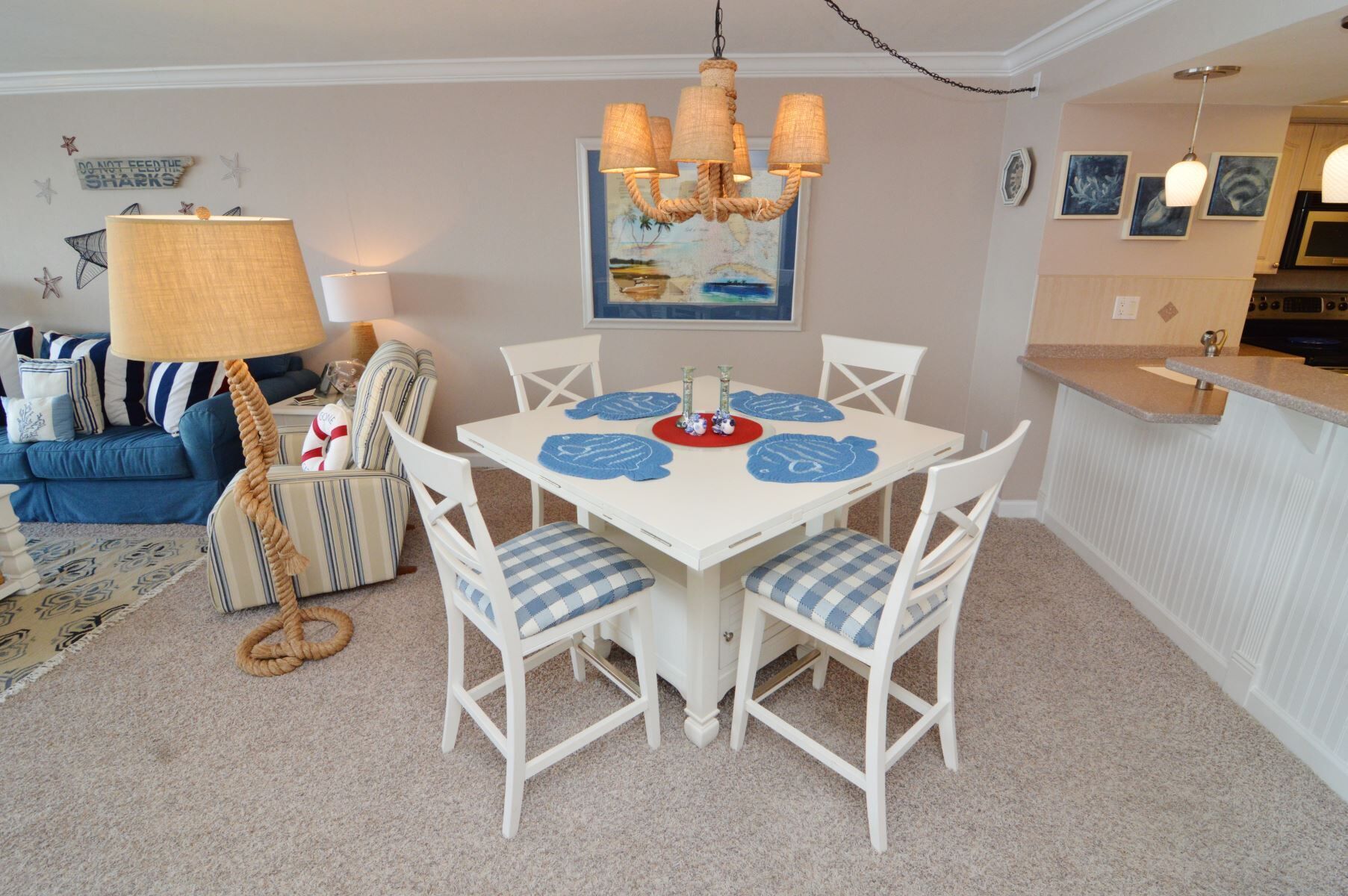 A dining area with a white table, blue placemats, and white chairs.