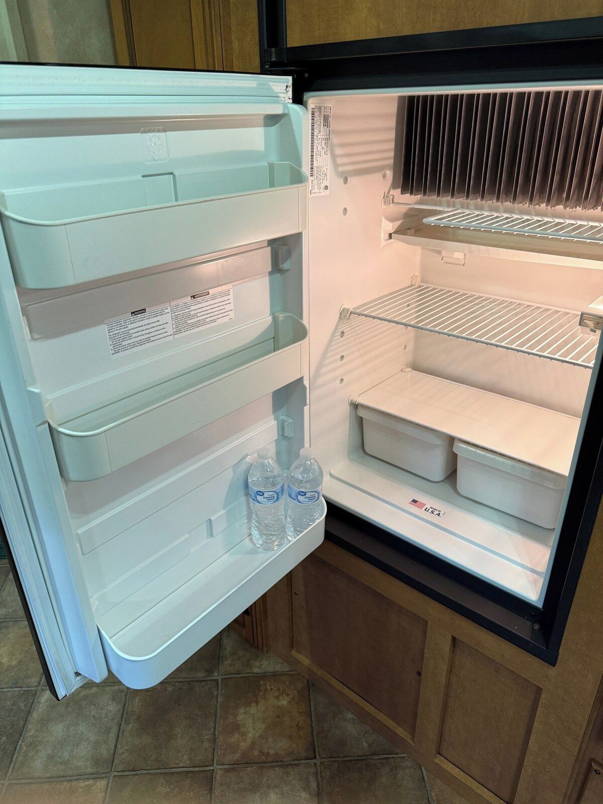 Avoin jääkaappi, jossa on useita hyllyjä ja pakastelokero.