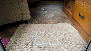 A pet door with a paw print design on a textured mat.