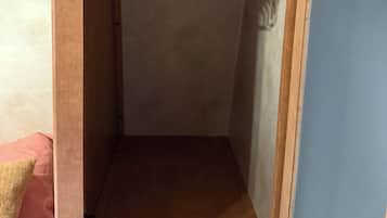 Un armadio con una porta in legno, un'asta appendiabiti bianca e un pavimento marrone.