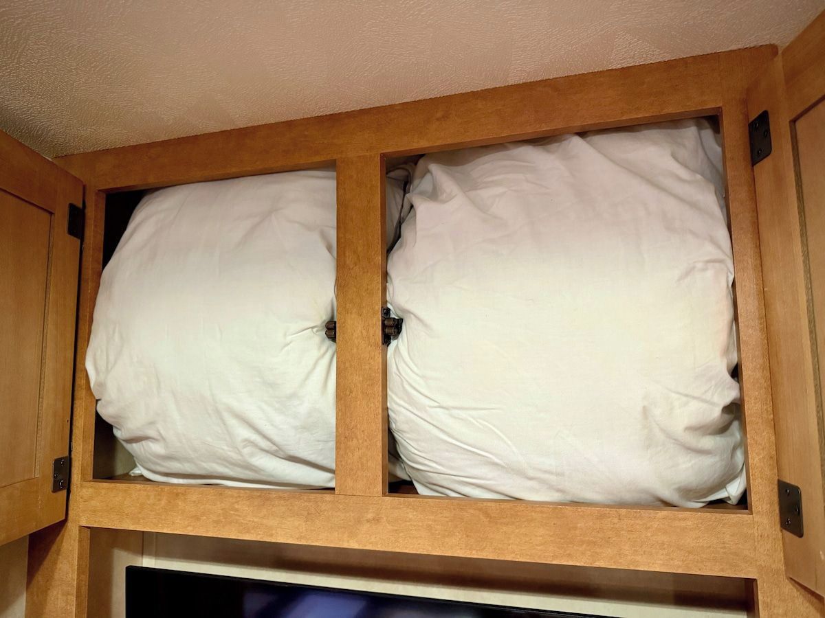 A wooden cabinet with two white pillows inside.